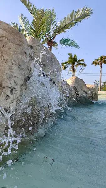 Каскад воды по валунам с пальмами