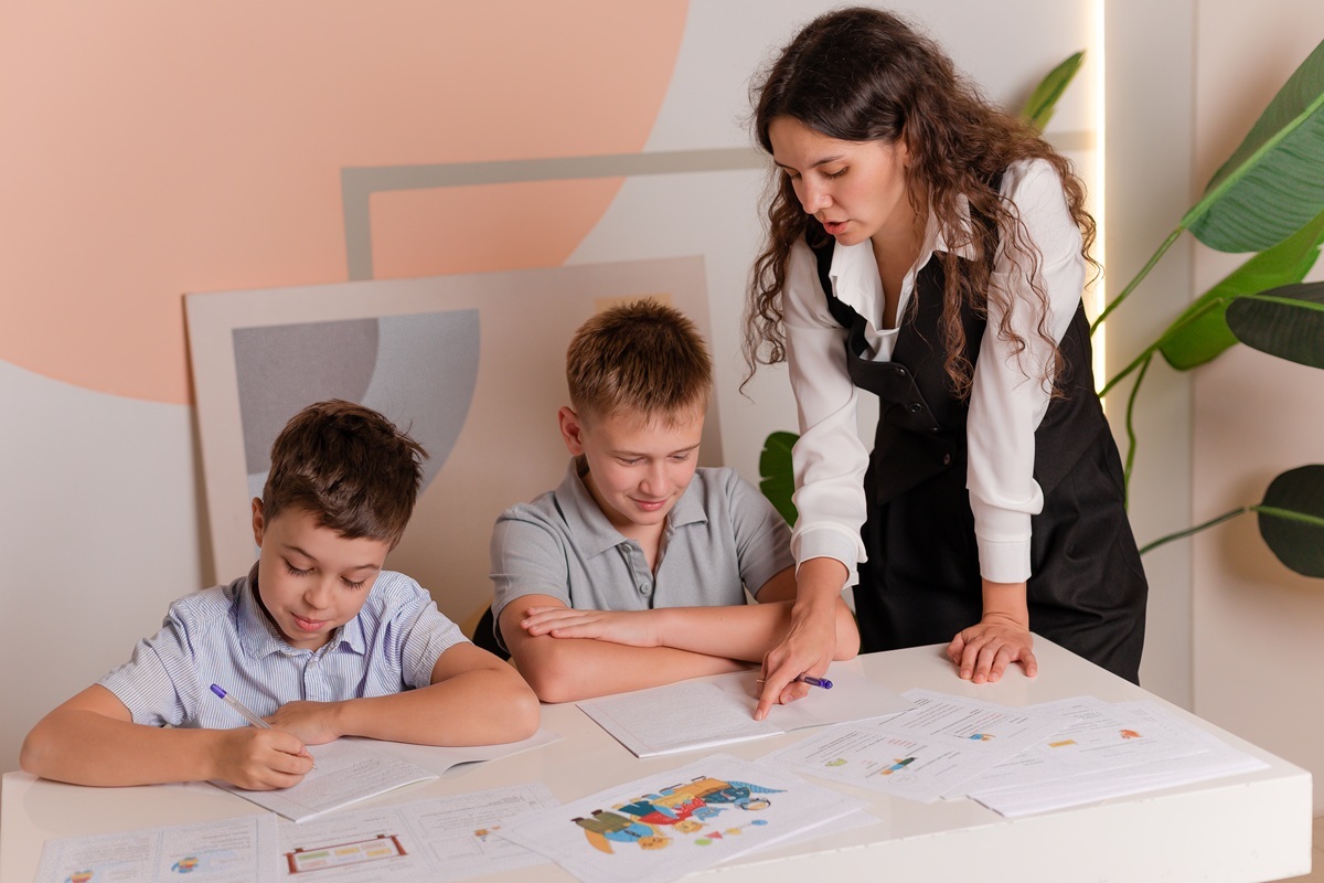 Педагог помогает школьникам выполнять письменные задания и развивать навыки чтения и письма