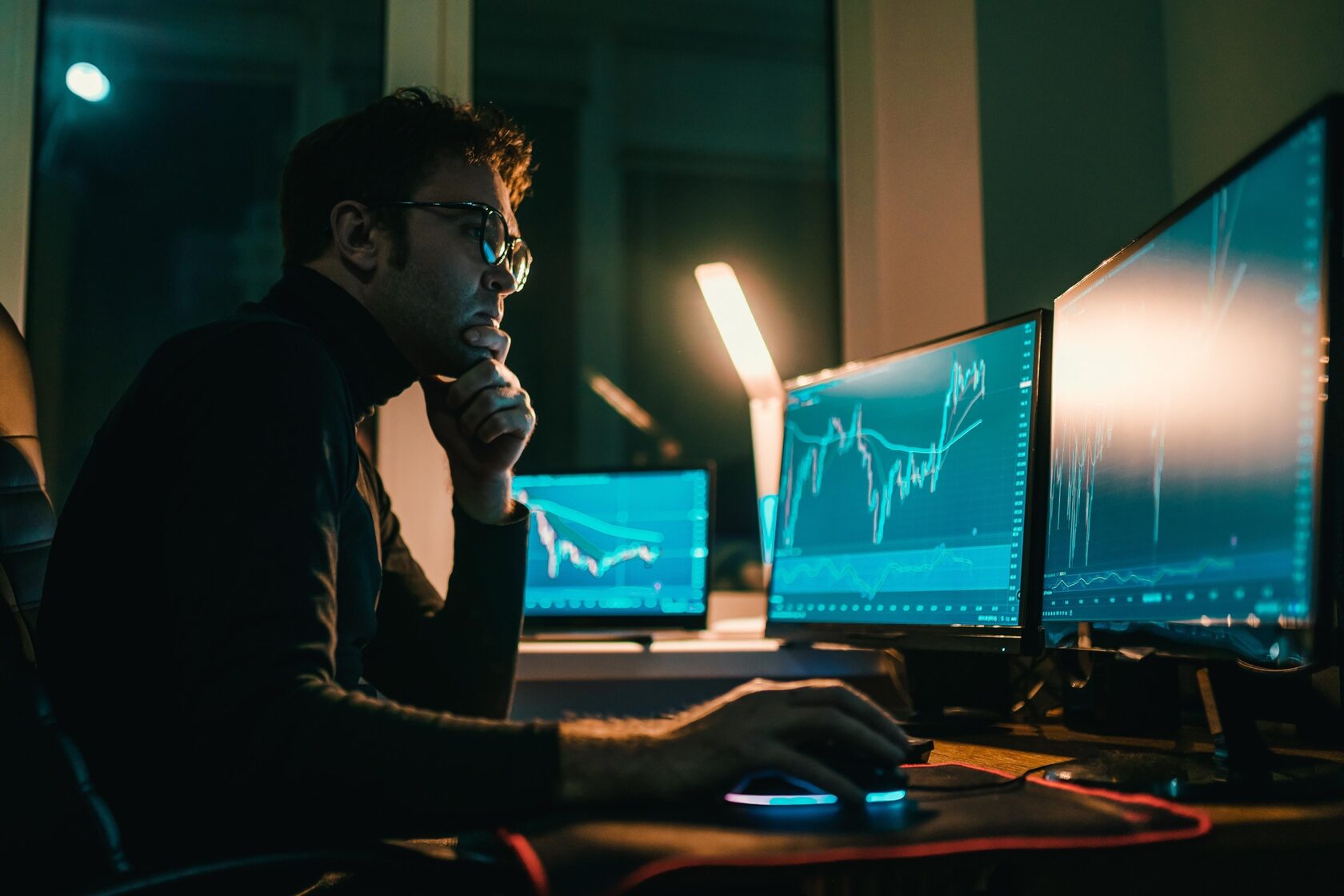 Человек в диспетчерской безопасности перед множеством экранов с аналитическими графиками, символизирующий информационную безопасность и анализ рисков.