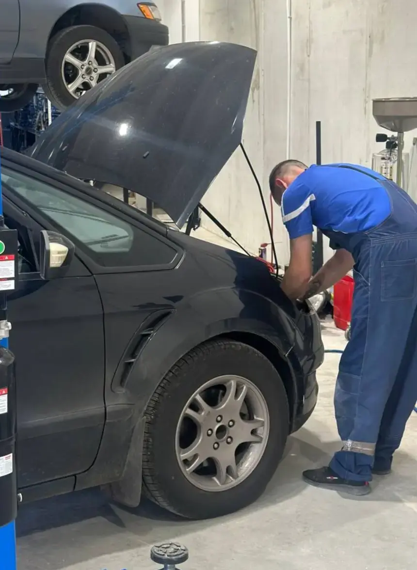 Мастер БАМ-АВТО в Красноярске работает в моторном отсеке автомобиля