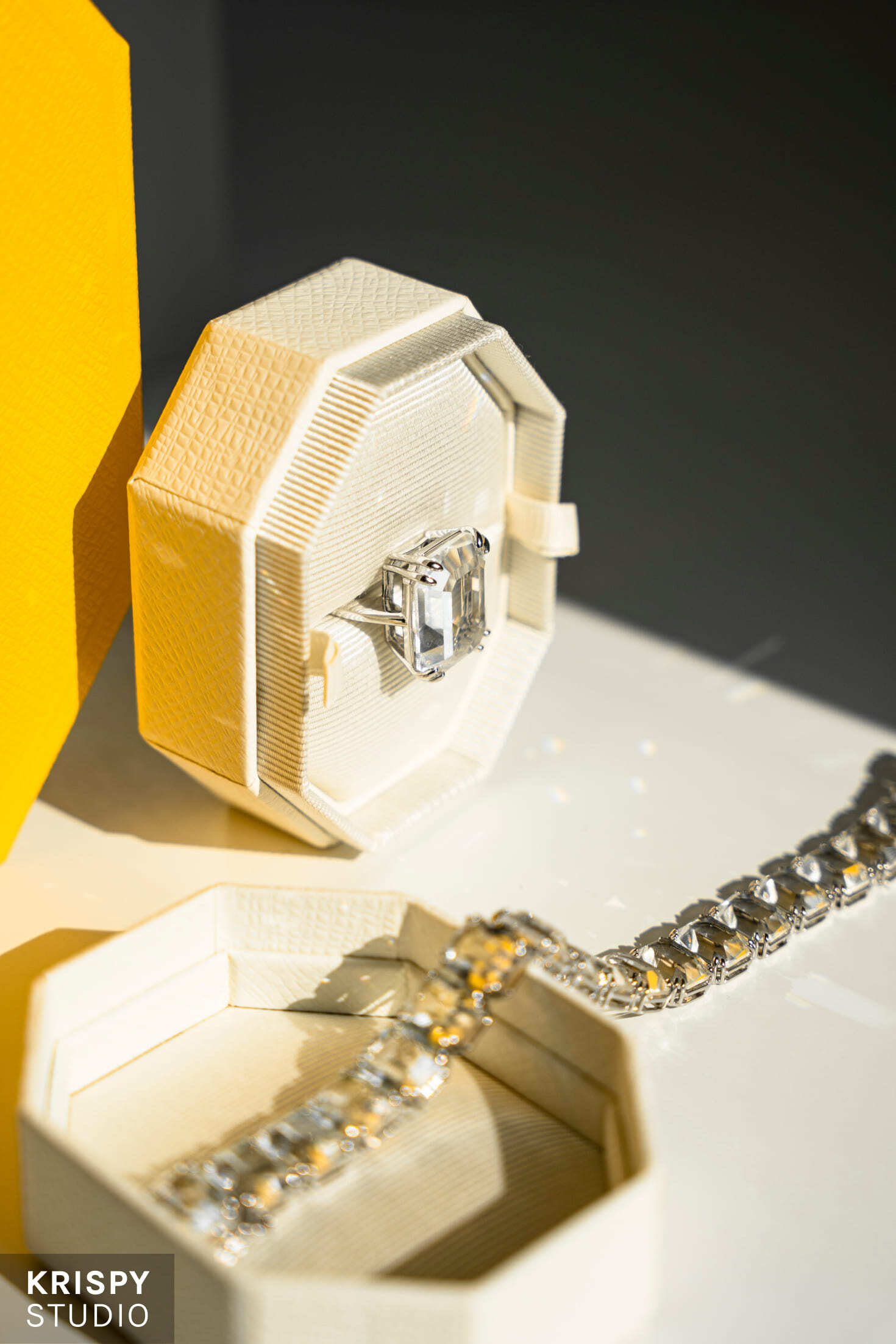 Кольцо и браслет Swarovski на белом фоне с фирменной желтой упаковкой, подчеркивающей элегантный стиль бренда.