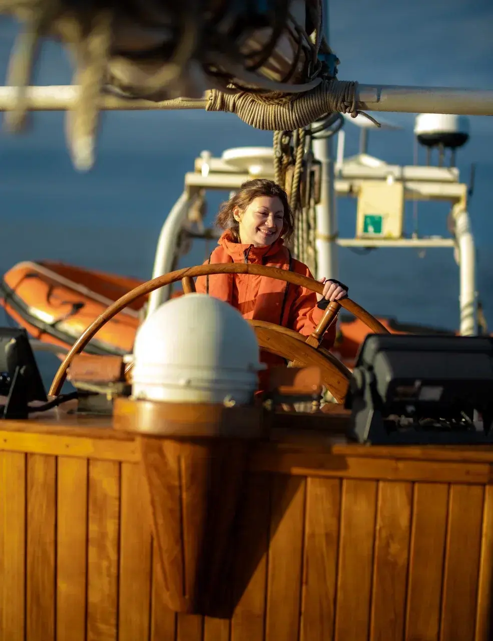 Guest taking the helm during an Antarctica sailing expedition. Under the guidance of the professional crew participants have the opportunity to steer the yacht themselves becoming an active part of the voyage rather than simply observing from the deck.