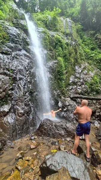 Мужчина купается под струёй водопада