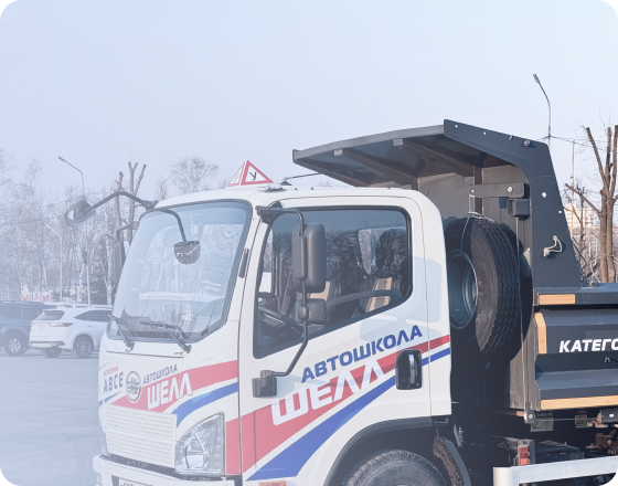 Черно-бронзовый мотоцикл стоит на стоянке у серого бетонного здания, вид сбоку