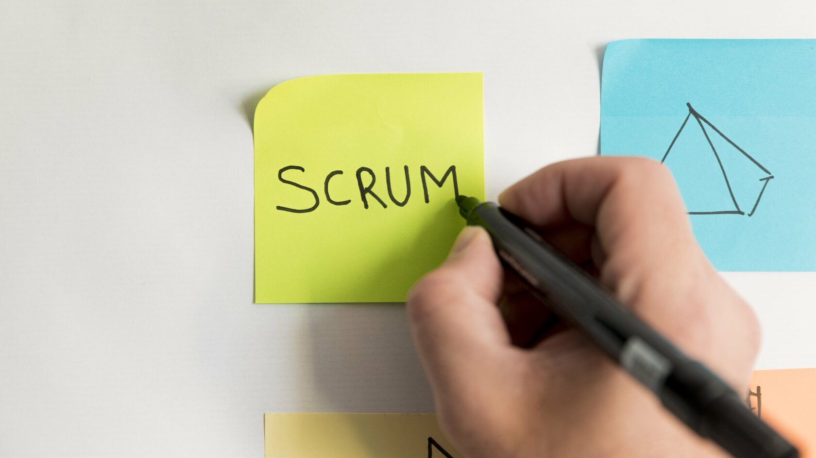 Человек пишет на стикере слово scrum