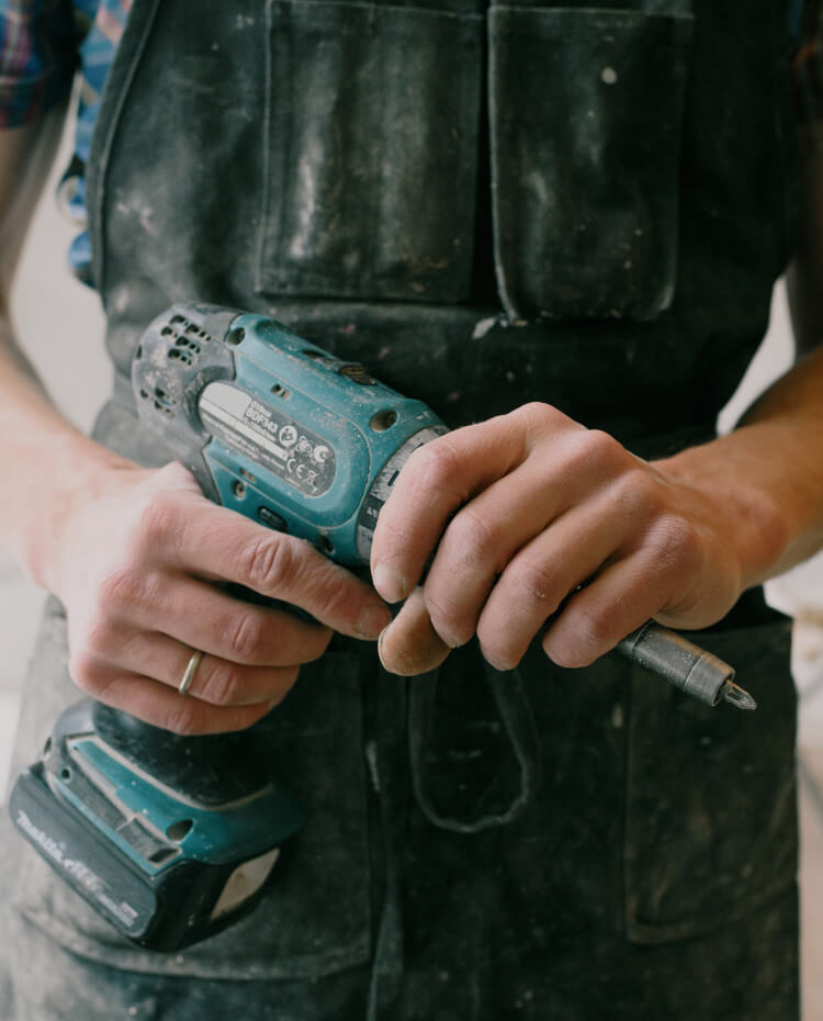 Ein Handwerker hält einen Akkuschrauber in seinen Händen