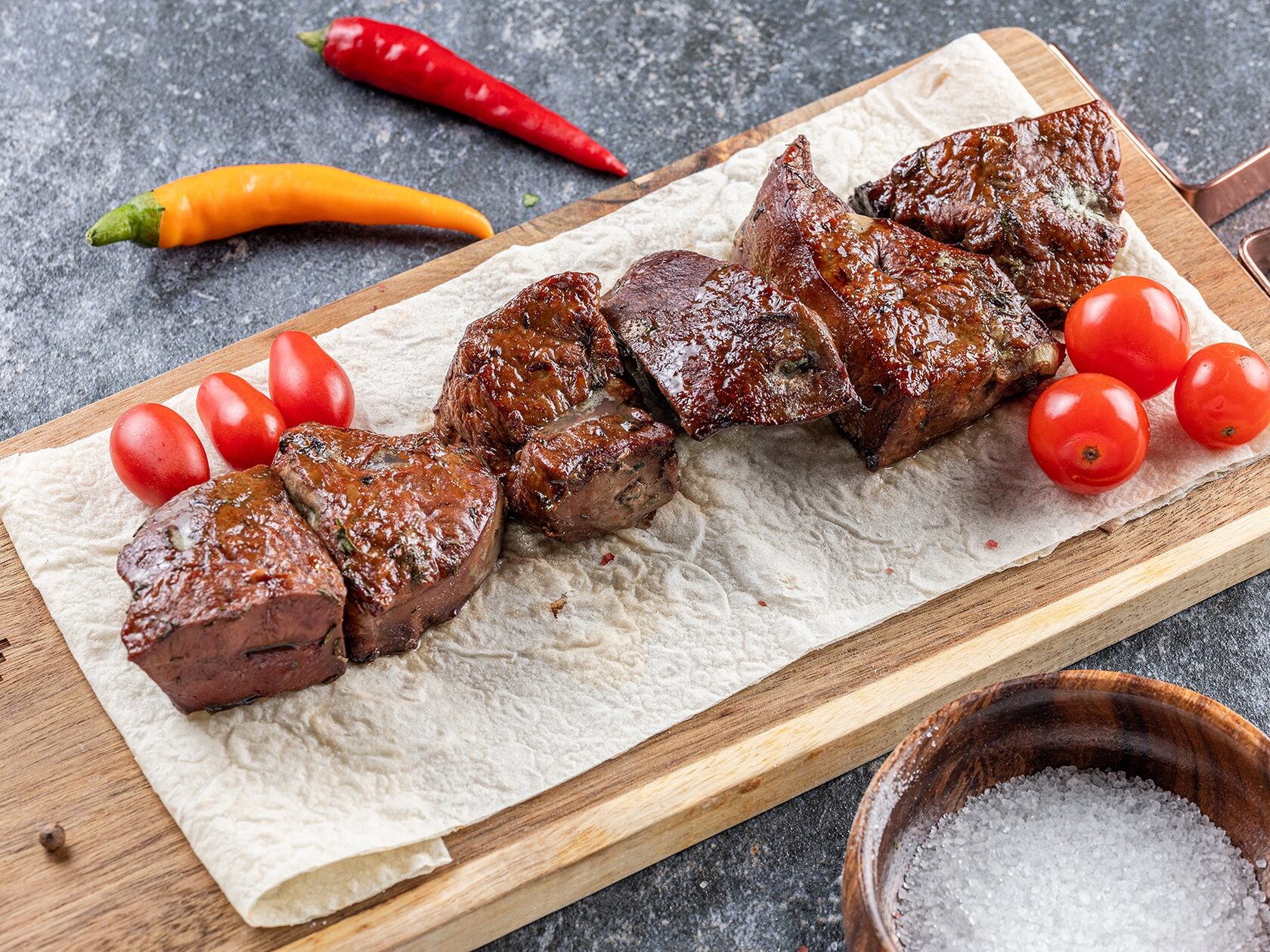 Шашлык из свиной шейки на деревянной доске с луком и соусом