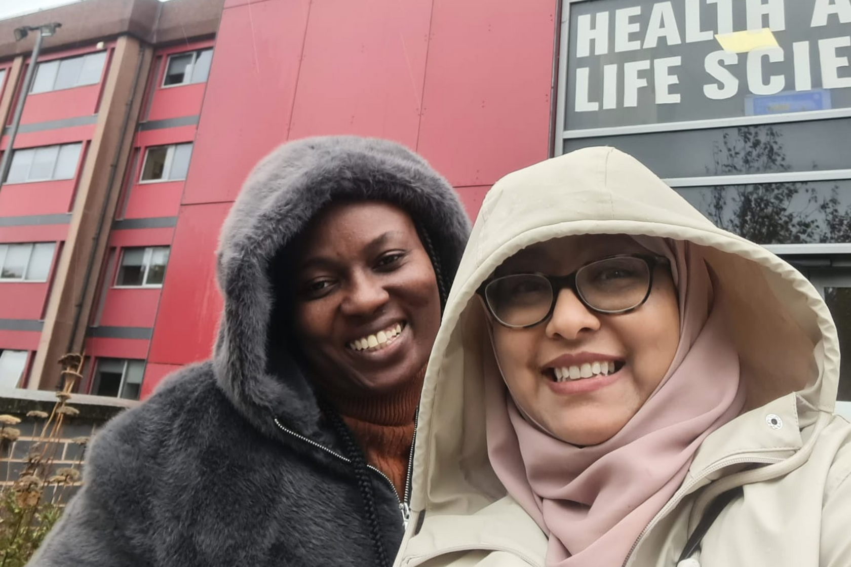 People smiling in front of a Health and Life Sciences building