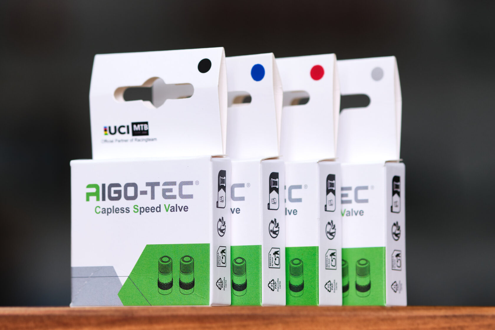 Четыре коробки с клапанами AIGO-TEC Capless Speed Valve на деревянной поверхности