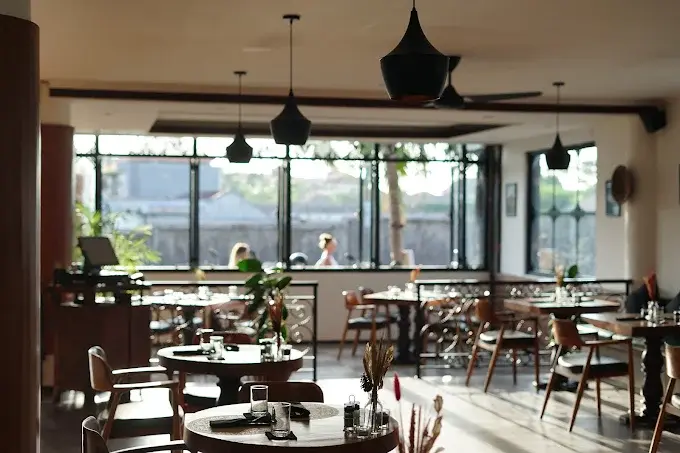 Elegant and grand interior of Casa Blanca Bali, a Baroque-inspired dining room with a curved staircase and centerpiece tree, known for its homemade pasta and live music.