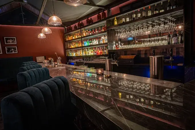 A sleek marble counter and beautifully illuminated liquor shelves inside White Rabbit, a moody speakeasy serving serious cocktails among the best bars in Bali.