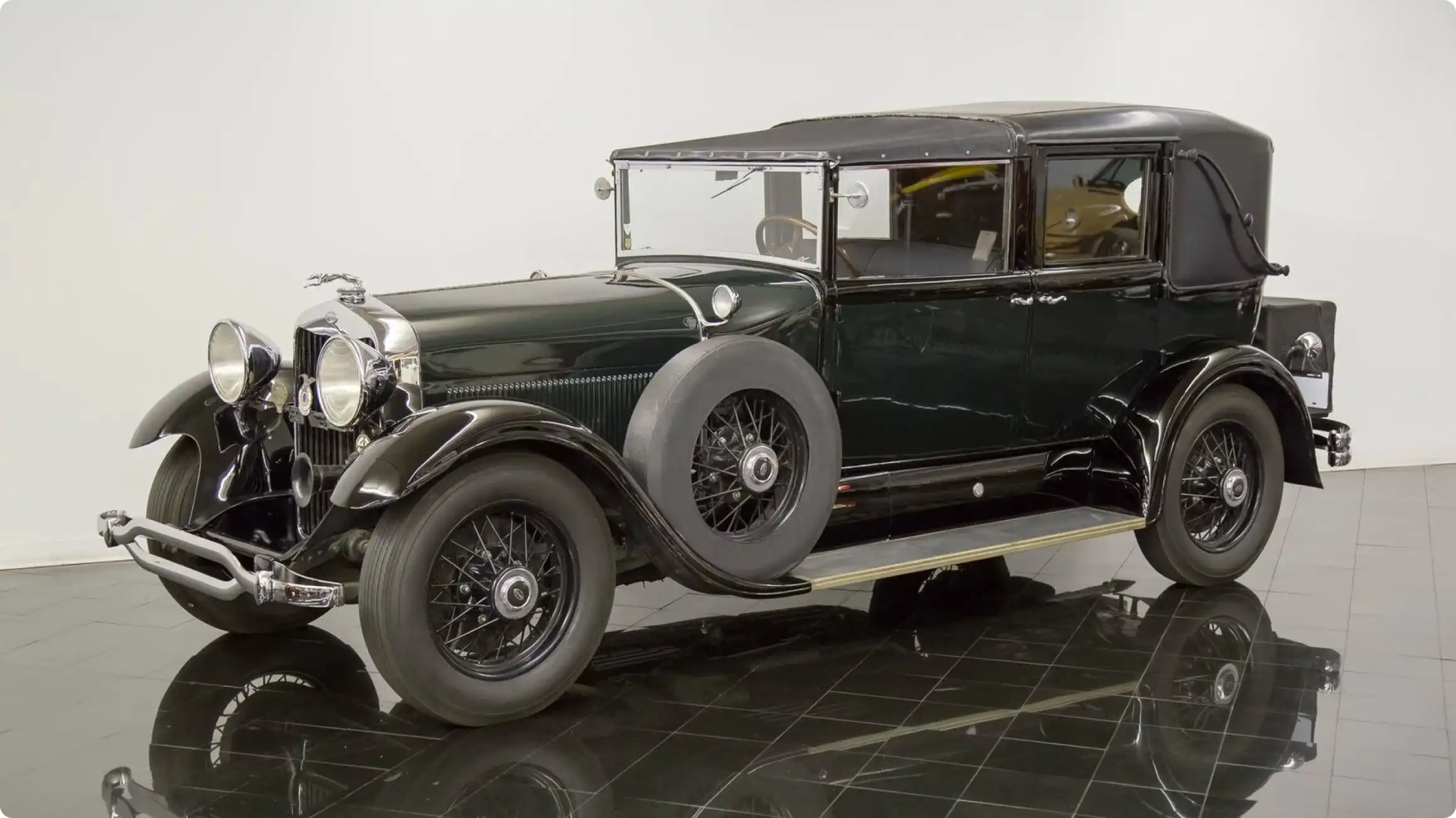 Роскошный классический автомобиль Lincoln Model K 1930-х годов в темно-зеленом цвете с запасным колесом на боку, выставленный в музее.