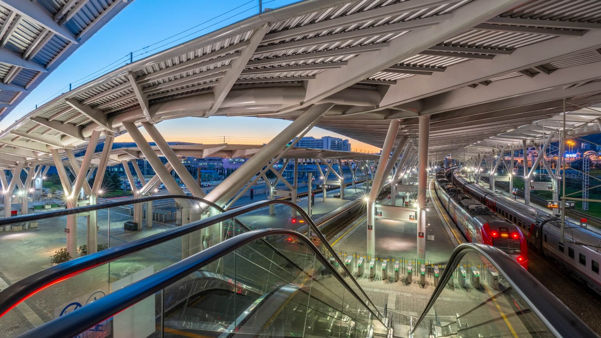 Эскалатор и перроны вокзала «Олимпийский парк», станция «Сириус» — поезд у платформы на закате, Сириус