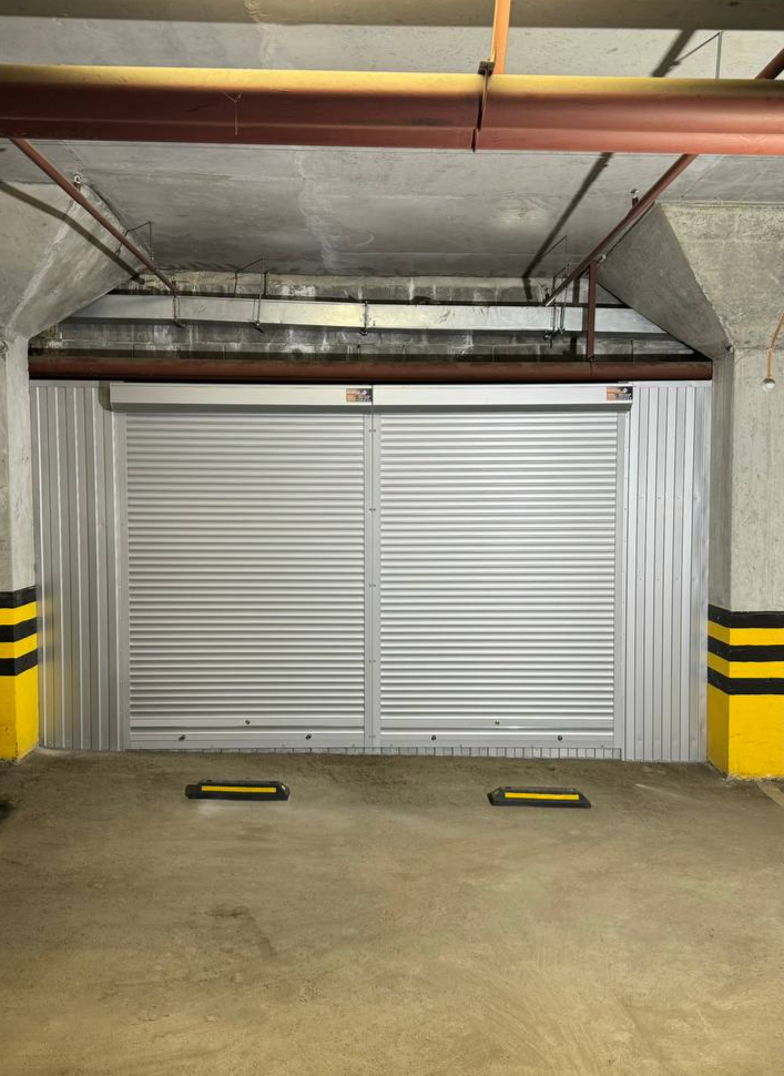 Шкаф-кладовая в паркинг (MaxParking) серебристого цвета, из профлиста с роллетой и металлическими полками.