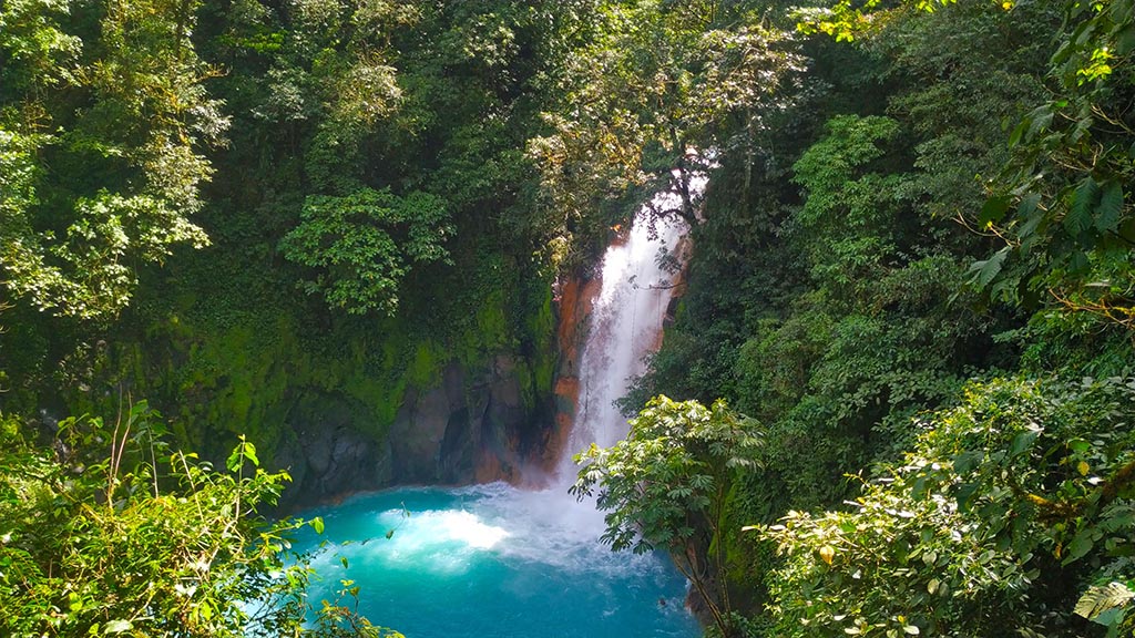 Rio Celeste waterfall flowing into a blue pool in tropical forest