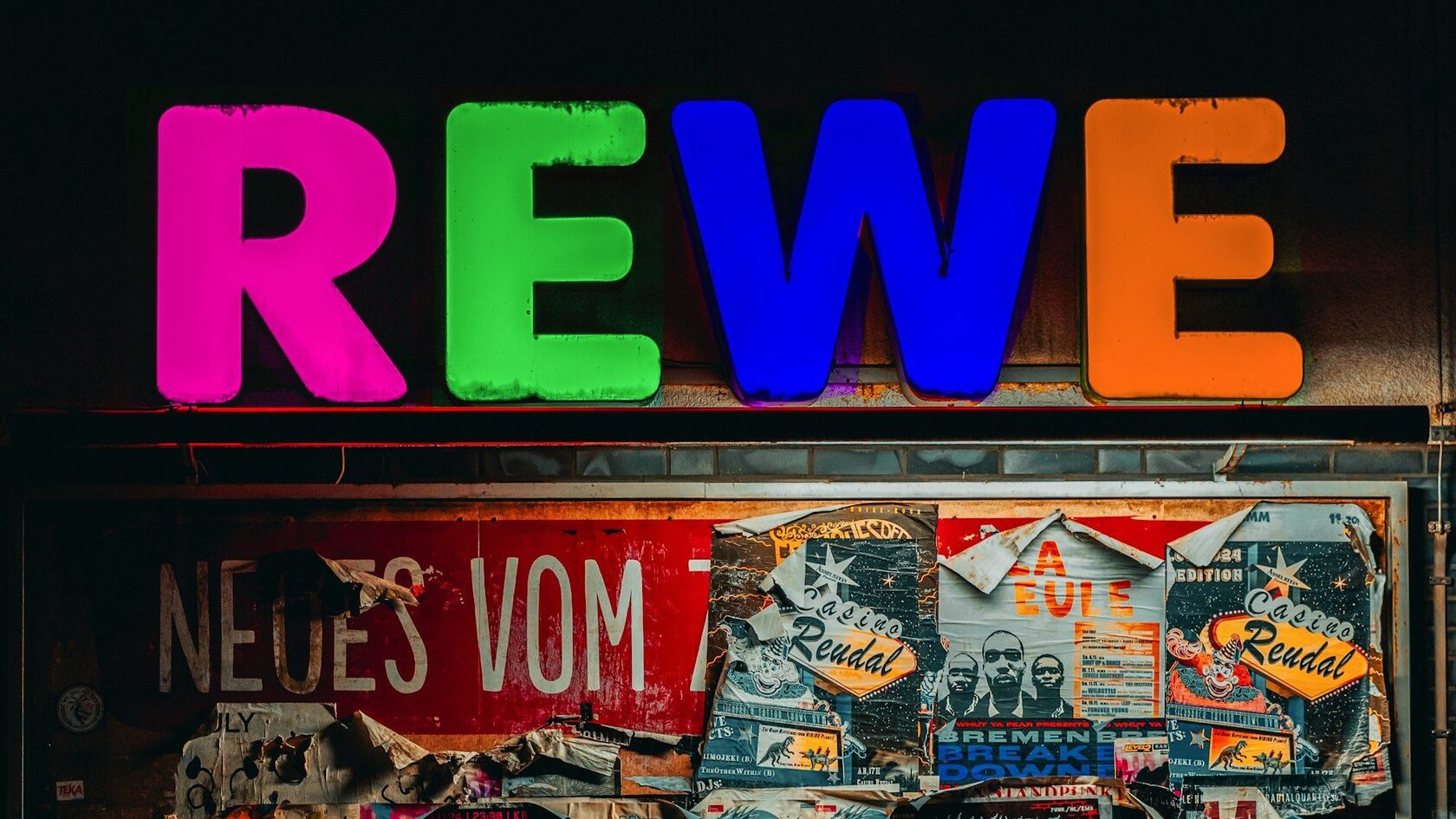 Illuminated REWE letters above a shop front