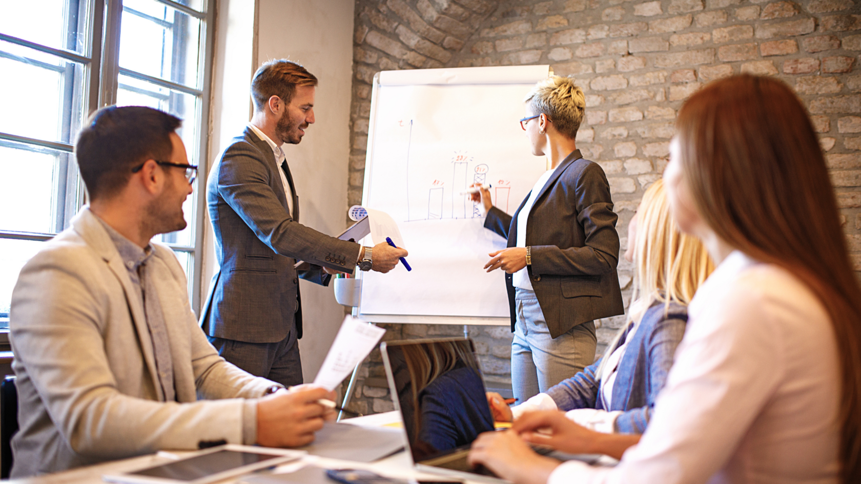A group of professionals looking at a large paper chart with financial information as they evaluate their debt load and consider venture debt.