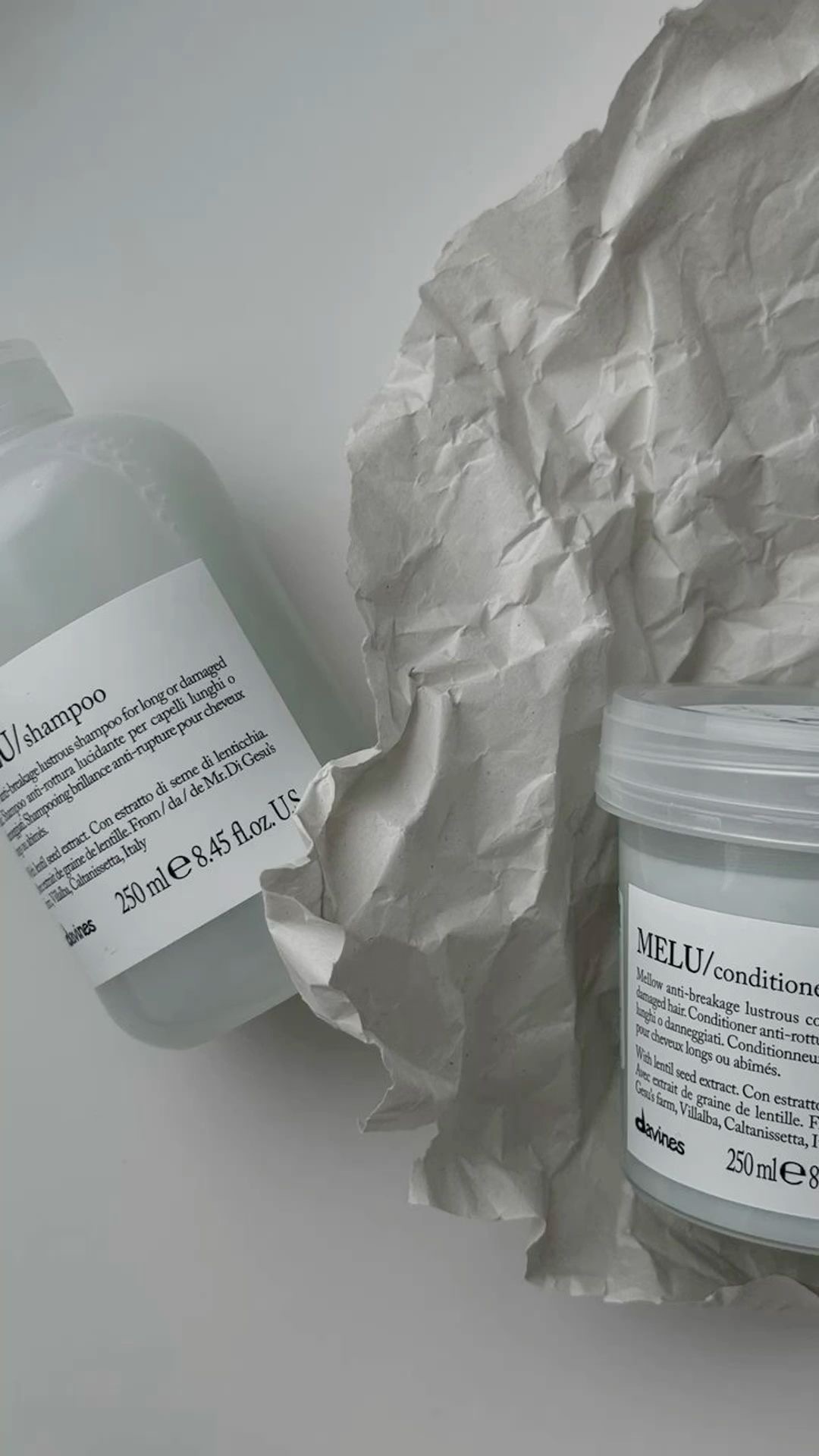 шампунь и маска лежат на мятой бумаге