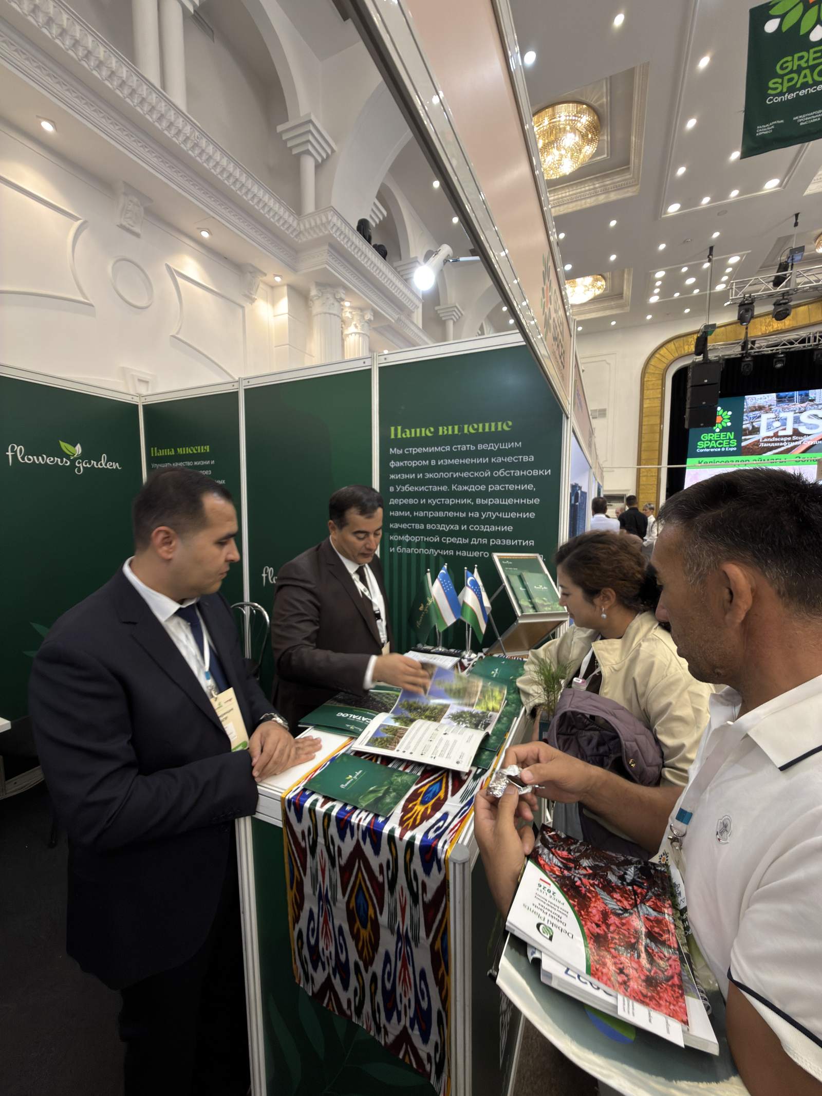 Сотрудники Flowers Garden показывают каталог растений посетителям выставки Green Spaces Expo 2026