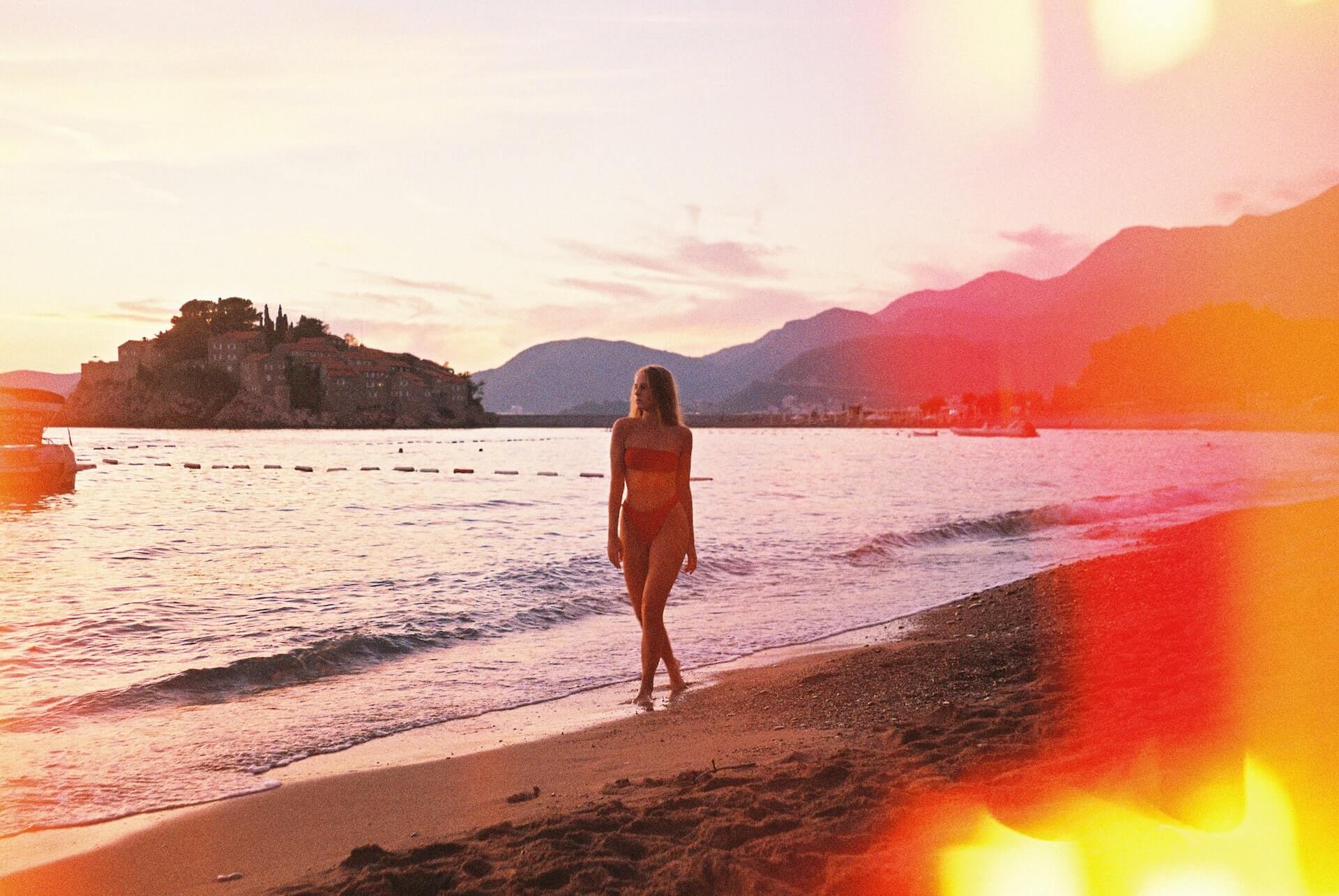 Guide to Montenegro - A woman walking on a beautiful sandy beach next to the sea in Montenegro
