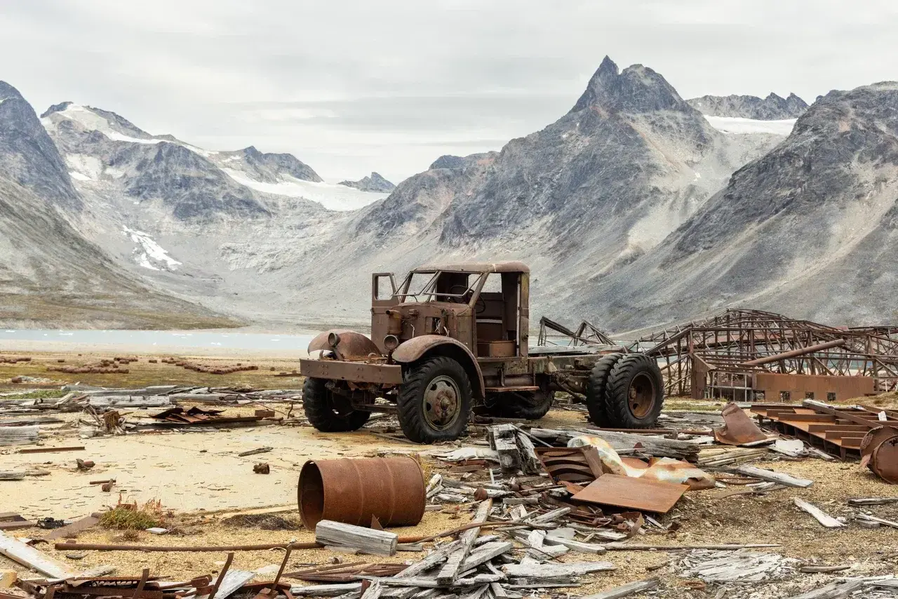 Discover the abandoned Arctic history of East Greenland, where rusting relics stand beneath towering mountains, glaciers and pristine fjords on an unforgettable sailing expedition.