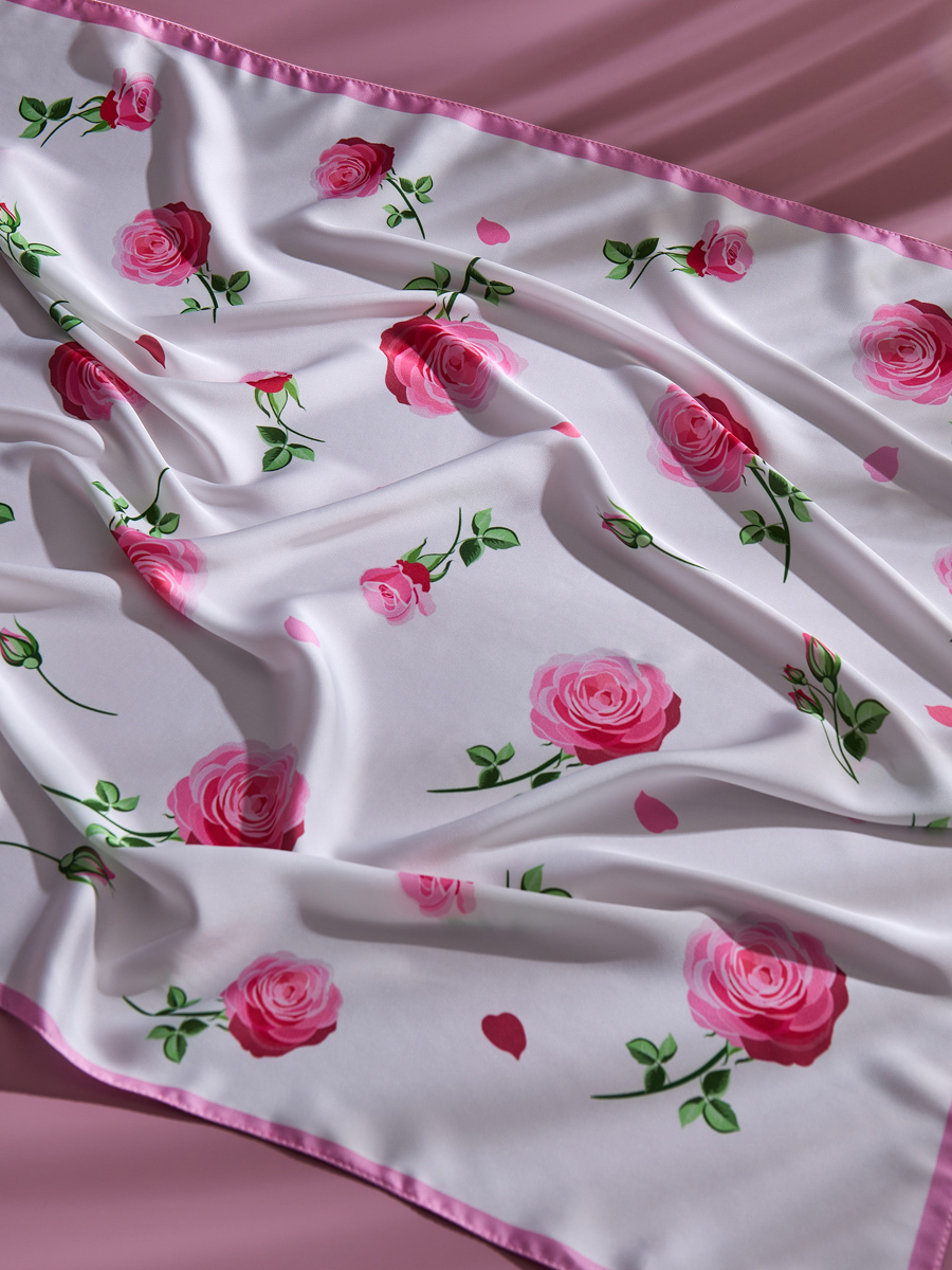 белый платок с узором цветка лежит на розовом фоне