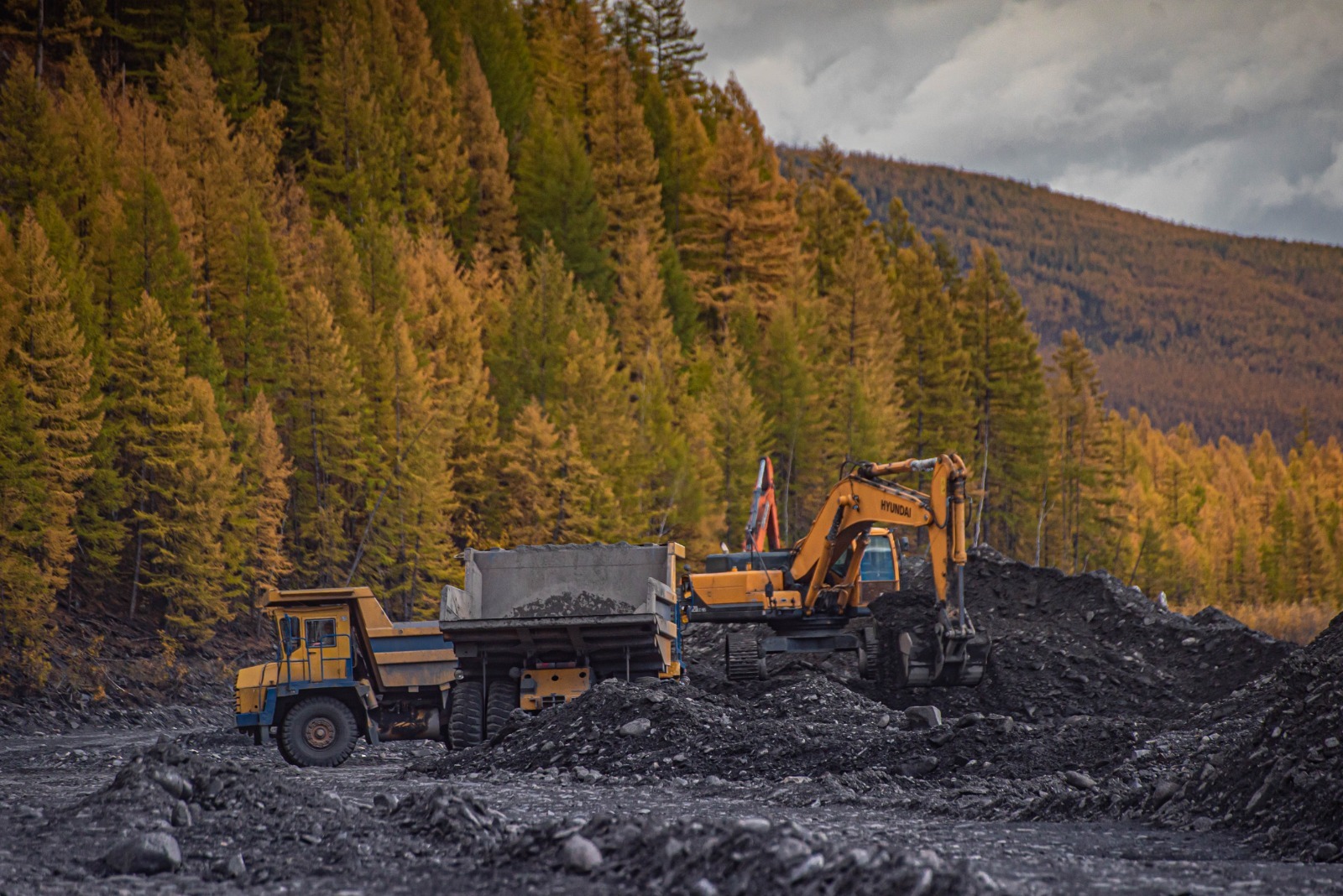 Экскаватор и карьерный самосвал на участке золотодобычи: открытые горные работы на Севере, добыча и погрузка горной массы