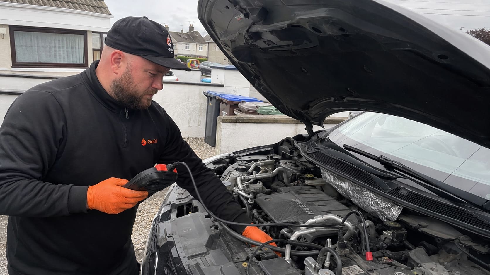 Mobile mechanic using a diagnostic scanner on a Nissan during a home car service