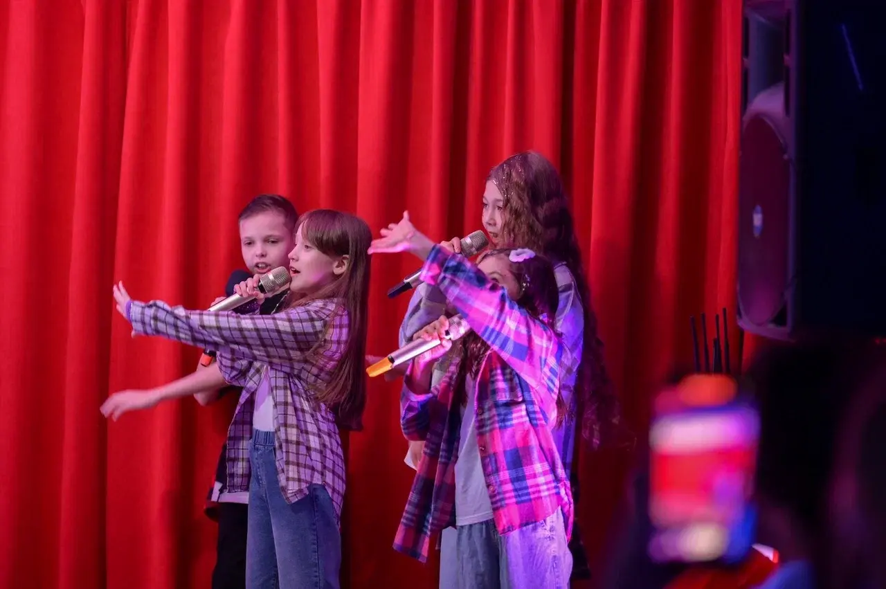 Дети выступают на сцене и поют в микрофон