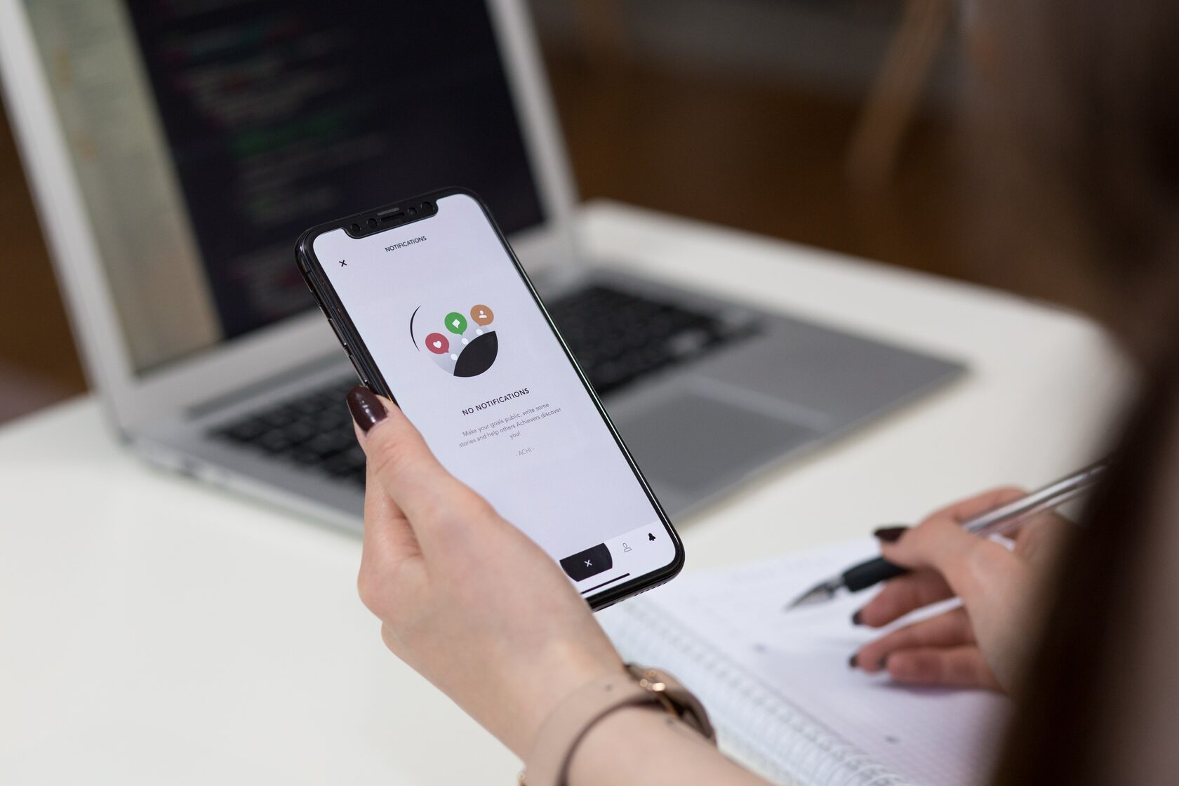 Woman looking at an app on an IPhone and writing