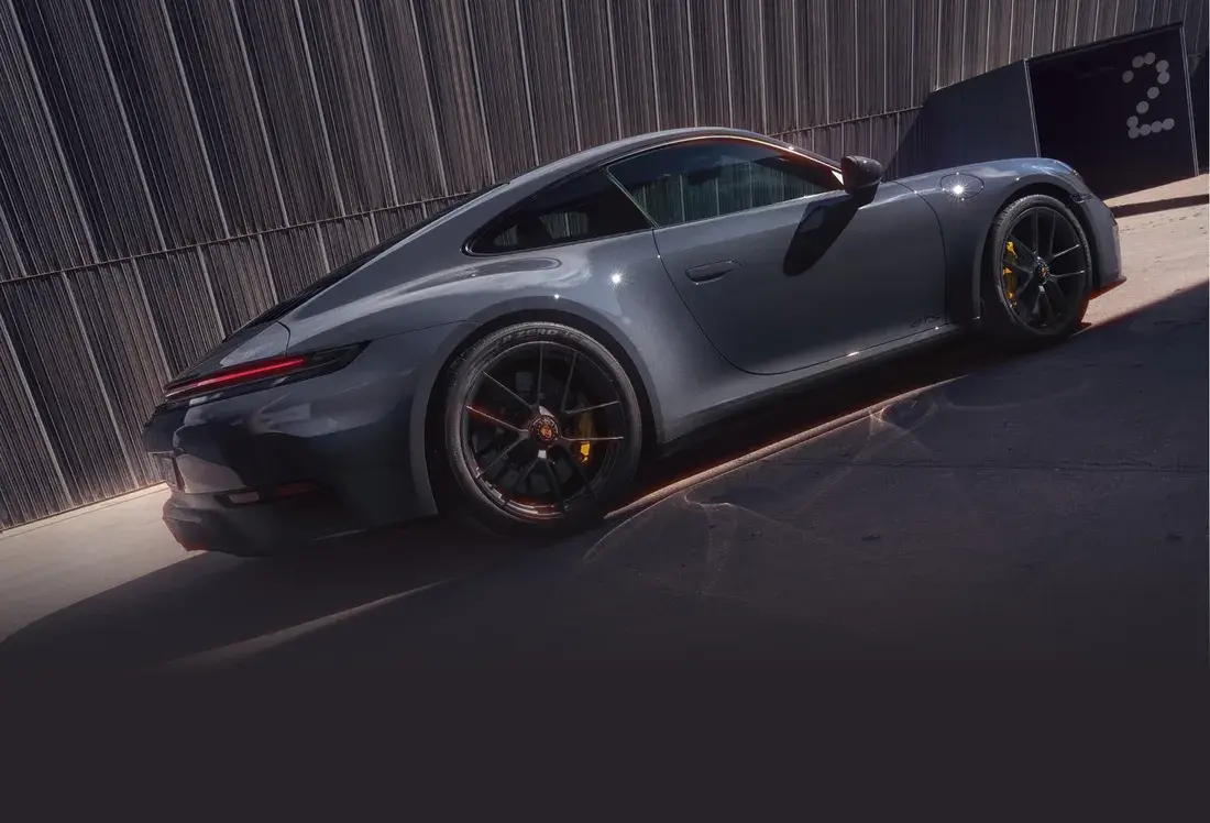 Porsche 911 Carrera GTS в цвете Schiefergrau neo у тёмно-серой стены