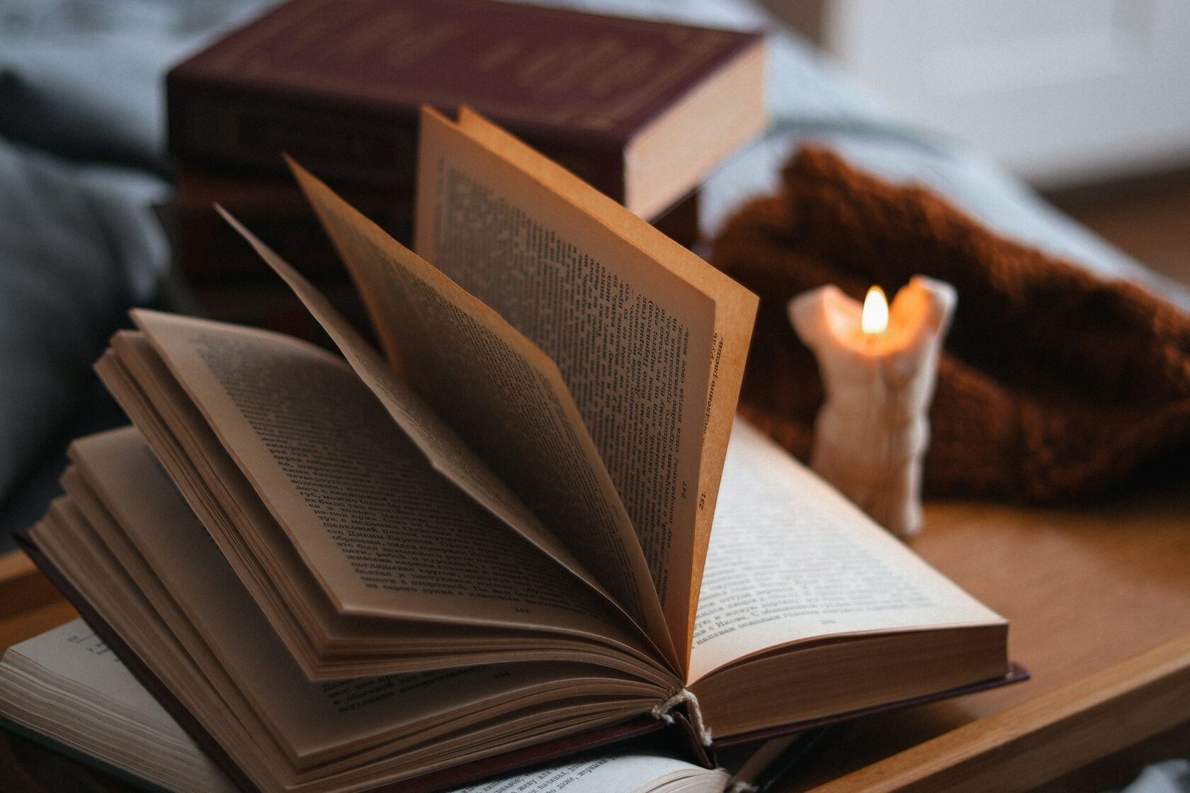 Тёплое свечение свечи и страницы открытой книги крупным планом