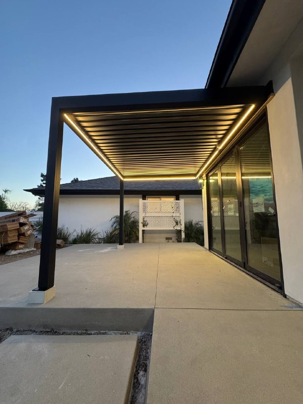Front-to-back view beneath the illuminated black pergola at blue hour.