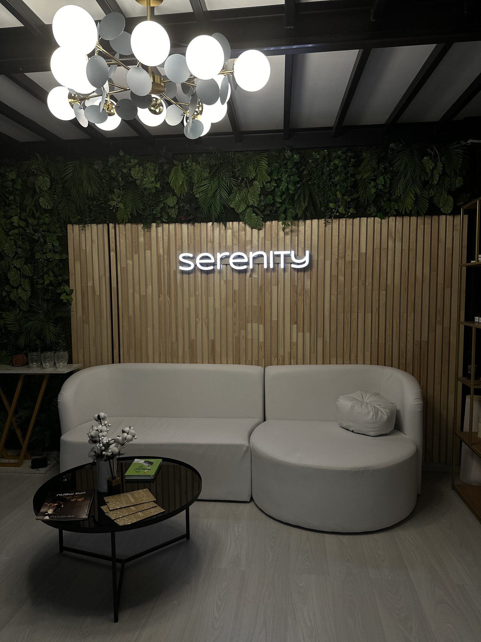 Зона ожидания в Serenity Тула с логотипом салона и светлым диваном