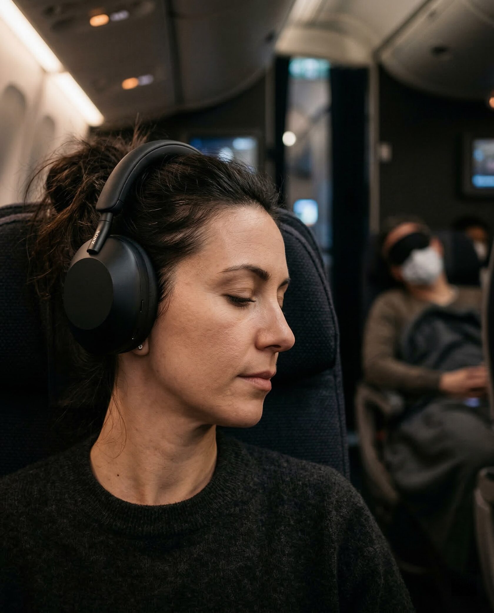  Пассажир в шумоподавляющих наушниках наслаждается музыкой, пока соседний пассажир мирно спит во время перелета.