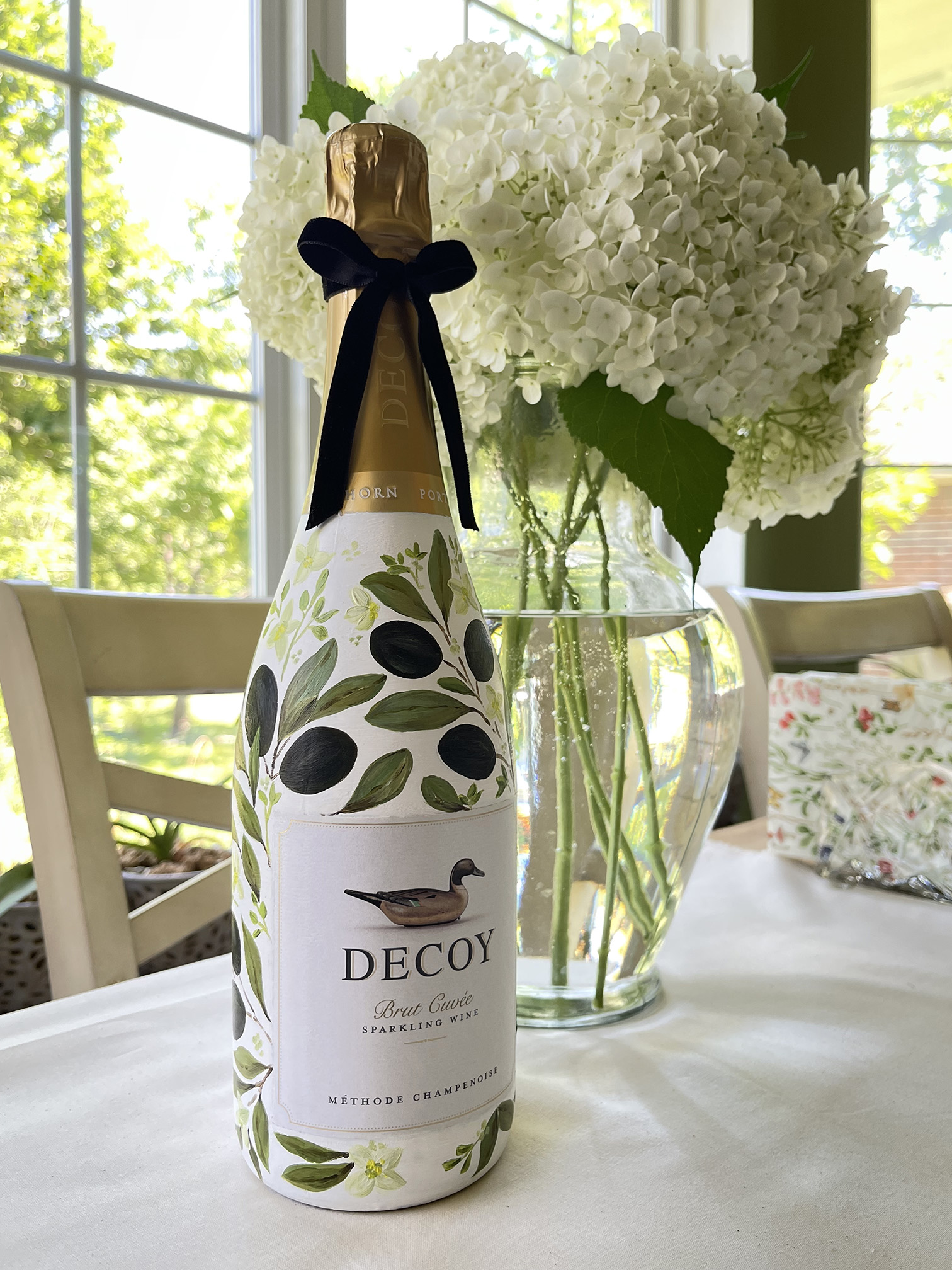 Decoy champagne bottle custom hand-painted with an elegant green olive branch design by Julia Razz.