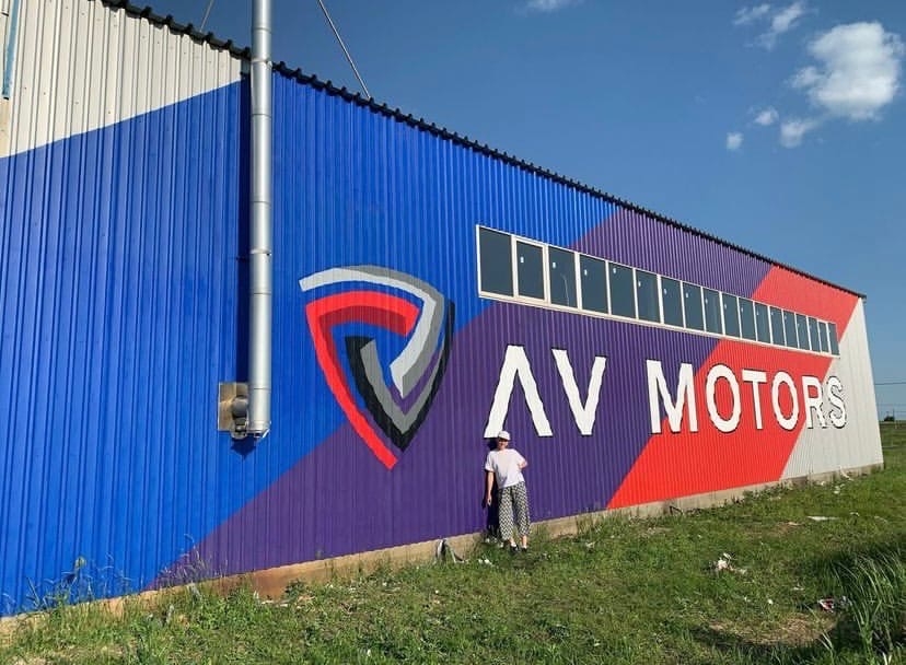 Мурал с логотипом AV Motors на фасаде промышленного здания