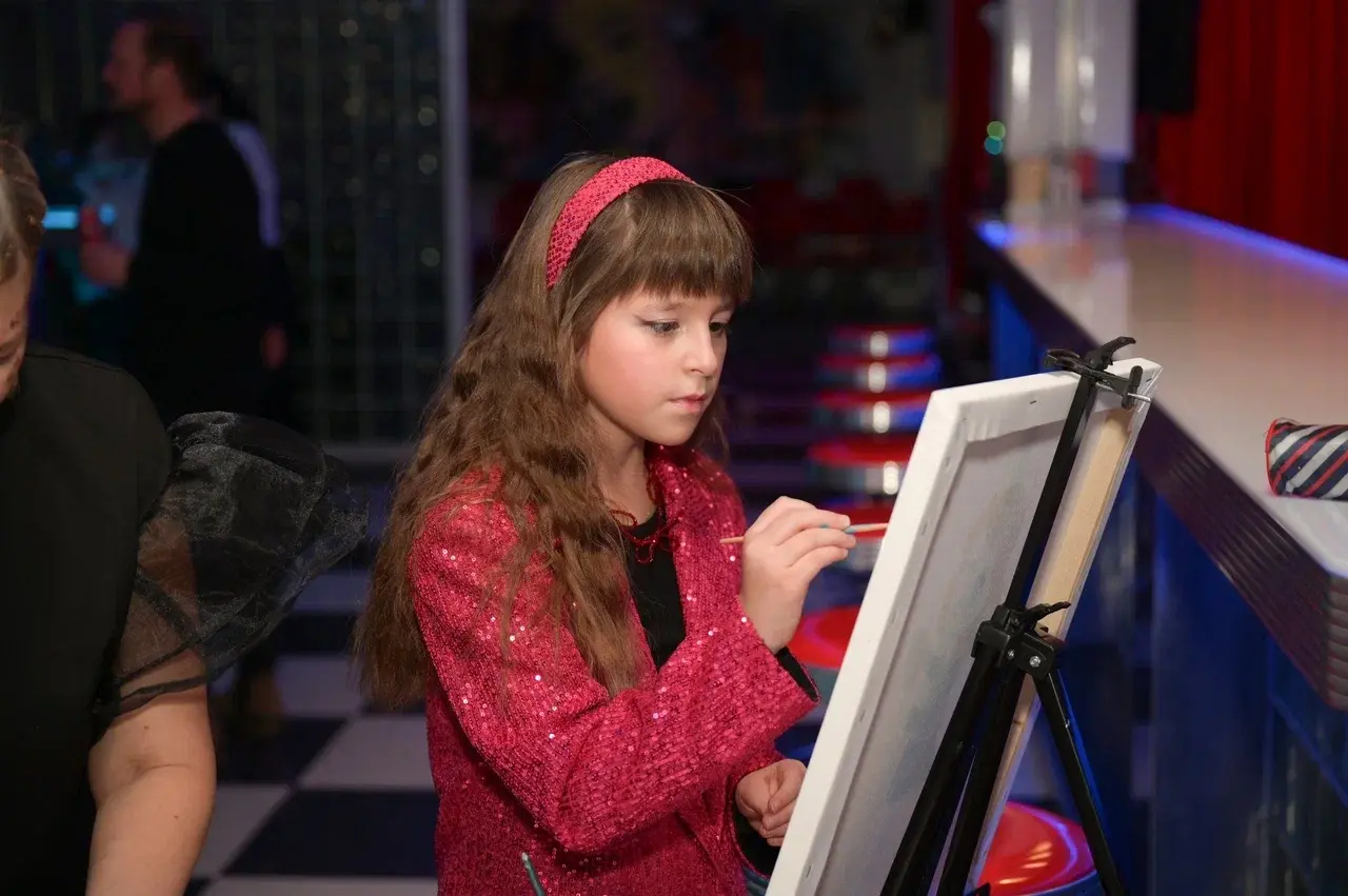 Девочка рисует на холсте