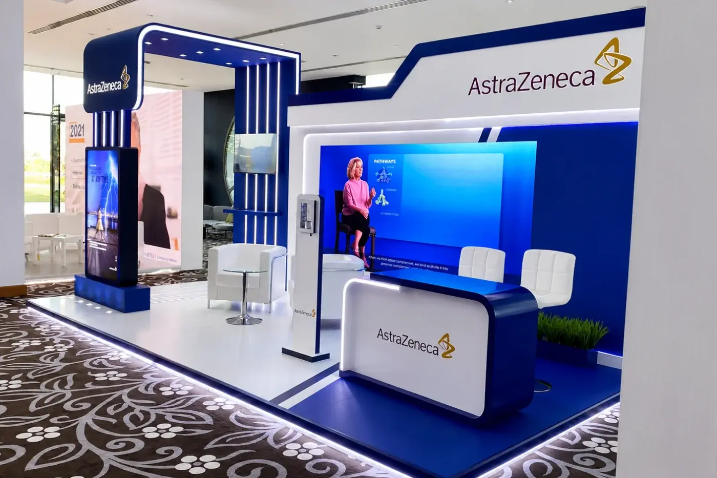 Exhibition stand with reception counter, display screens and a meeting area