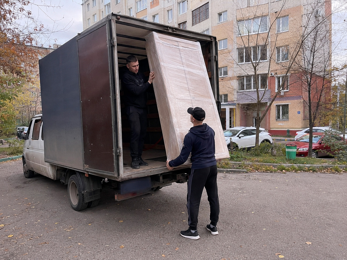Грузчики выгружают крупную мебель из автомобиля
