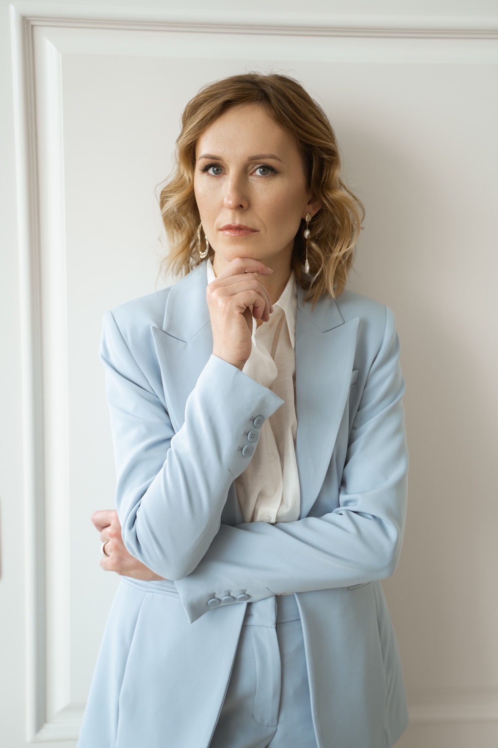 Екатерина Прийменко в голубом костюме у стены