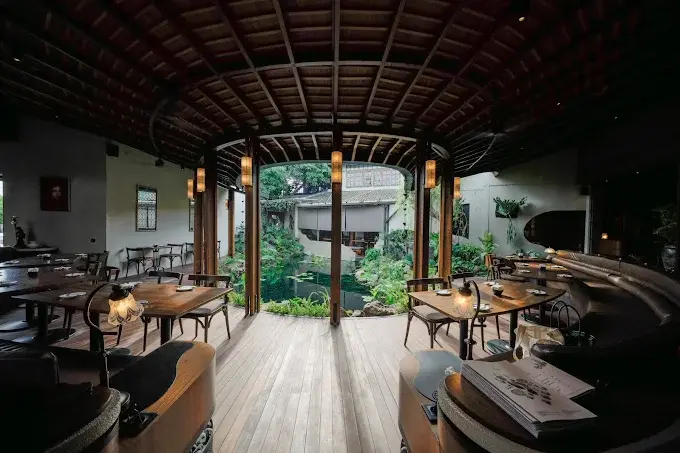 The peaceful indoor/outdoor dining area at Dahana Restaurant, featuring a beautiful central koi pond and garden. A relaxed spot for a diverse Japanese menu in Seminyak.