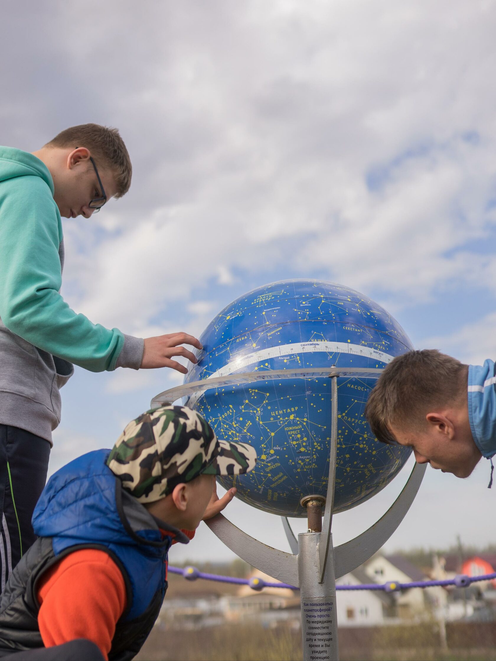 Ваня в белой футболке, зеленой куртке и синих джинсах перепрыгивает через перила лестницы