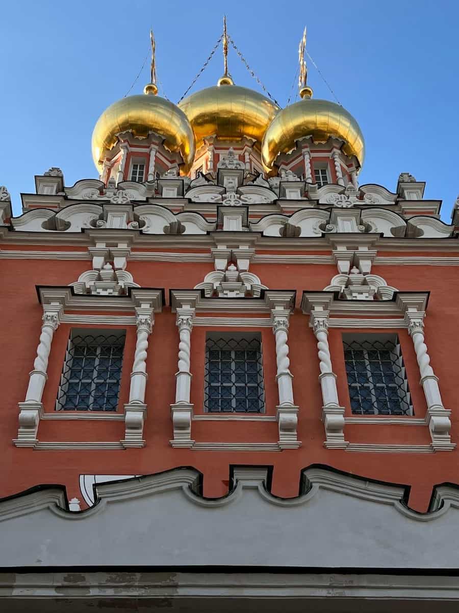 Красный церковный фасад с золотыми куполами в Кадашах