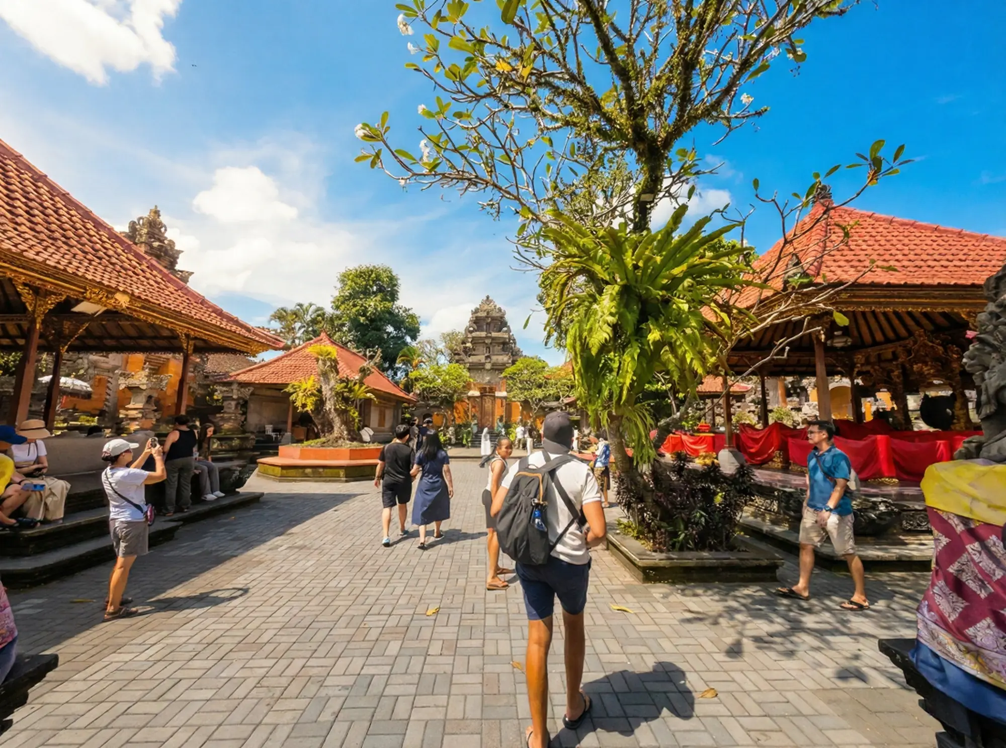 Tourists exploring the sunny main courtyard and traditional gates of Ubud Palace.