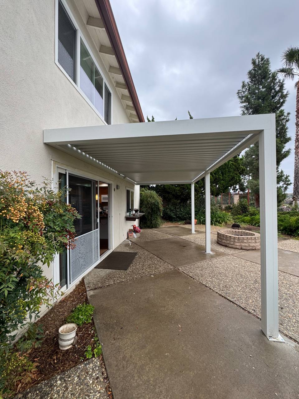 Installed pergola frame connected along a Fountain Valley home with posts on the concrete patio
