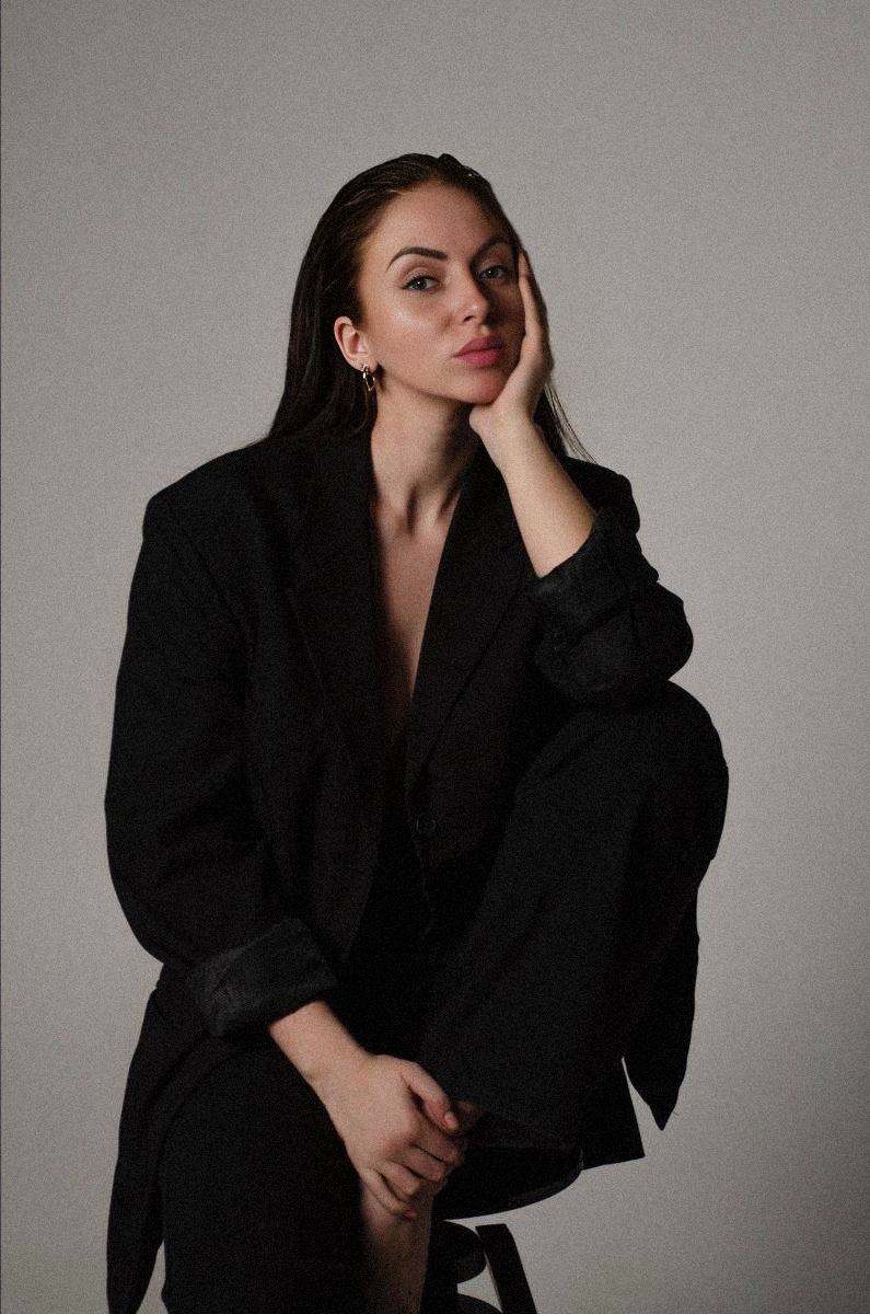 девушка на фото сидит на стуле рукой держит лицо