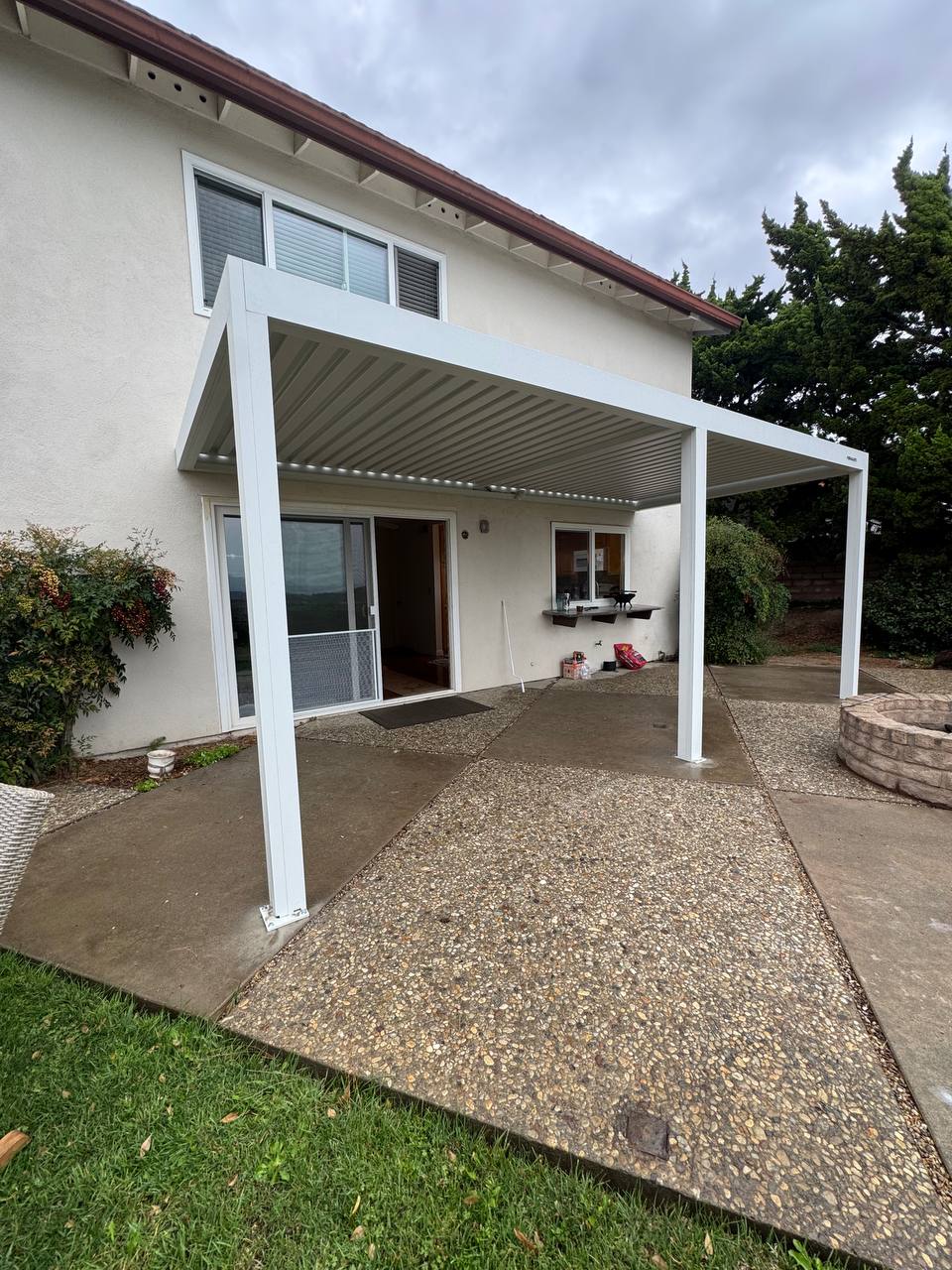 Close view of white aluminum pergola support post and louvered roof beside a California home