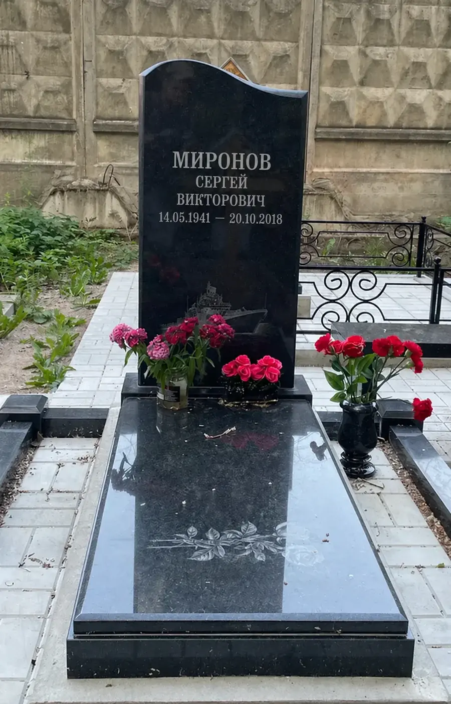 Надгробная плита с рисунком ветви перед вертикальным памятником