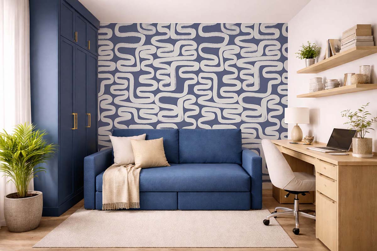 Современная комната с синим диваном, темно-синим шкафом, деревянным рабочим столом с ноутбуком, настенными полками и акцентной стеной с геометрическим узором в сине-белых тонах